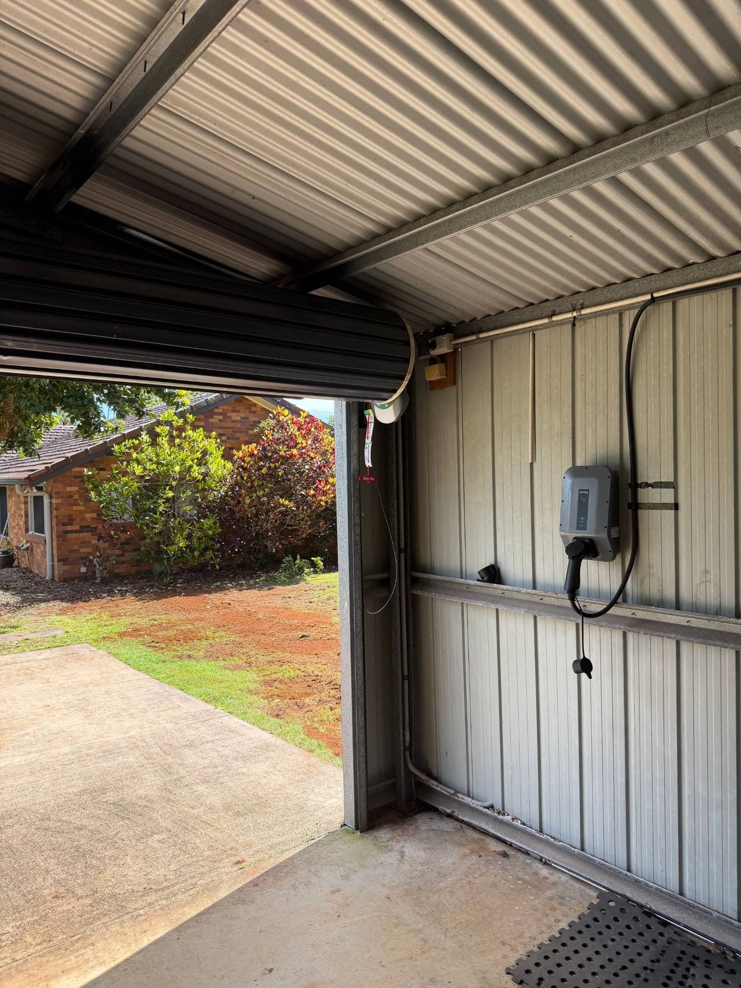EV charger installed on a carport wall next to the roller door